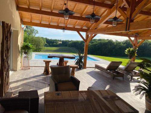 une terrasse avec une pergola en bois et une piscine dans l'établissement Le Refuge des Épicuriens, à Eymet