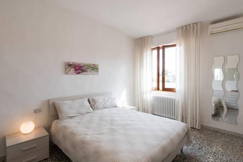 ein weißes Schlafzimmer mit einem Bett und einem Fenster in der Unterkunft La Casa di Lucia - Firenze in Florenz