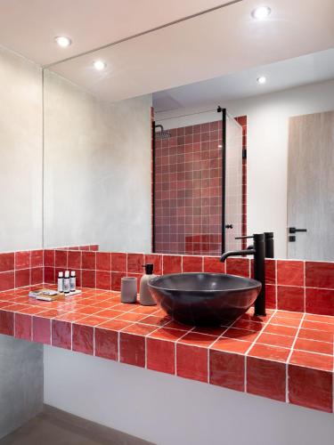 a bathroom with a black sink on a red tiled counter at Muse Urban Suites in Athens