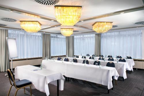 a conference room with white tables and chairs and chandeliers at Wyndham Stuttgart Airport Messe in Stuttgart