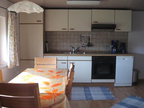 - une cuisine avec des placards blancs, une table et un évier dans l'établissement Haus Hörger, à Maierhöfen