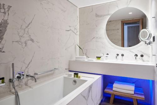 a bathroom with a tub and a sink and a mirror at Atlantica Caldera Palace in Hersonissos