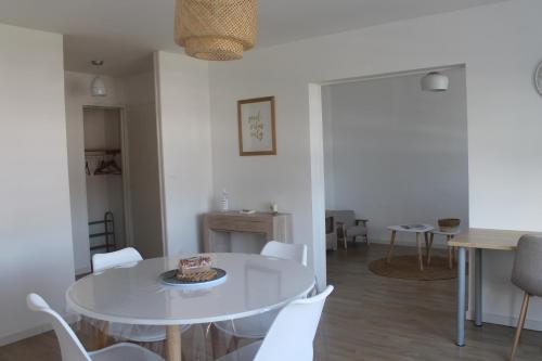 a dining room with a white table and white chairs at Appartement Dunkerque proximité plage et centre ville in Dunkerque
