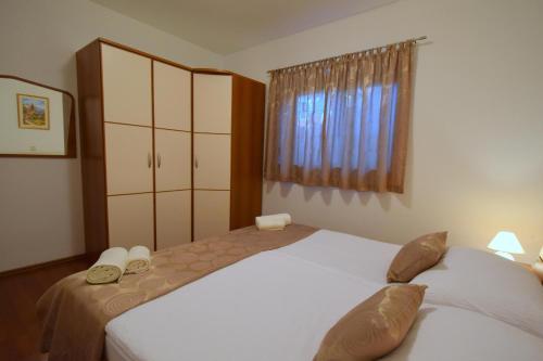 sypialnia z 2 łóżkami i oknem w obiekcie Apartments Jasmina w mieście Malinska