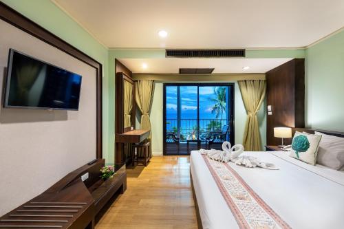 a hotel room with a large bed with a television at The Jomtien Twelve in Jomtien Beach