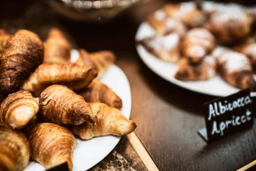 two plates of croissants and other pastries on a table at Solo Experience Hotel in Florence