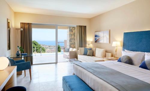 a hotel room with a large bed and a couch at Daios Cove Luxury Resort & Villas in Agios Nikolaos