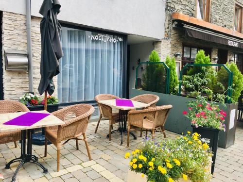 un patio esterno con tavoli, sedie e fiori di Nocturno a La-Roche-en-Ardenne