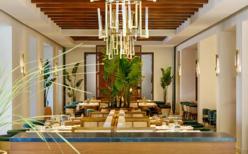 uma longa sala de jantar com mesas e um lustre em Daios Cove Luxury Resort & Villas em Agios Nikolaos