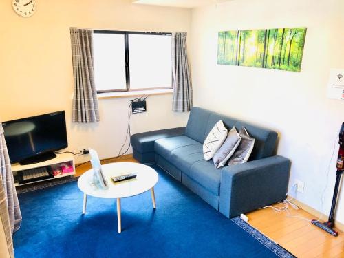 a living room with a blue couch and a table at Espoir Inn 1-201 in Kumamoto
