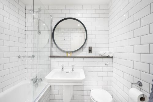 Baño blanco con lavabo y espejo en The Ballachulish Hotel, en Glencoe