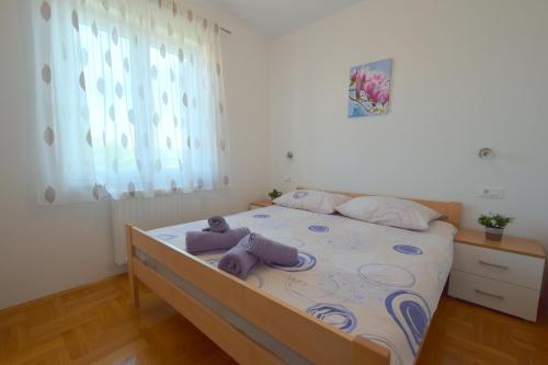 - une chambre avec un lit et des serviettes pourpres dans l'établissement Apartment Baran, à Čižići