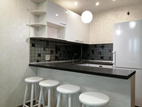 a kitchen with white cabinets and white stools at Апартаменты in Kirov