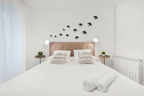 ein weißes Schlafzimmer mit einem großen weißen Bett mit Fledermäusen an der Wand in der Unterkunft MintyStay - Luca de Tena in Madrid