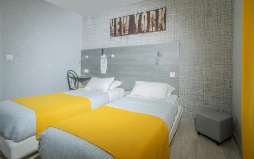 two beds in a room with yellow and white at Hôtel Mac Bed in Poitiers