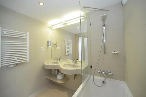 a bathroom with a sink and a glass shower at Hôtel de la Baie - Thalassothérapie PREVITHAL in Donville-les-Bains