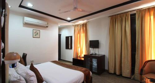 a bedroom with a bed and a tv and a window at HOTEL VEER PALACE in New Delhi