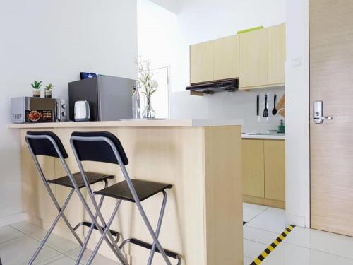 a kitchen with two chairs at a kitchen counter at Skypod Residence Puchong in Puchong