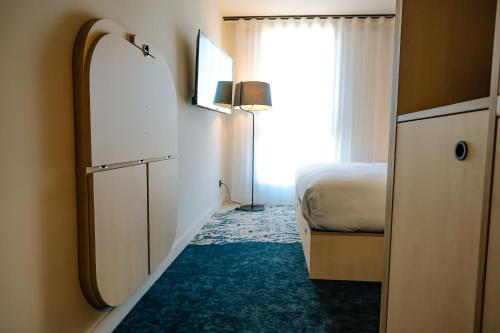 a hotel room with a bed and a window at Live Hotels Bordeaux Lac in Bordeaux