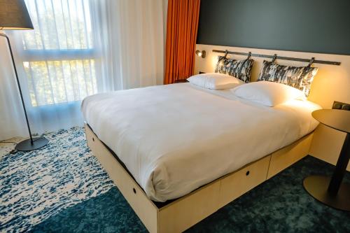 a large bed in a hotel room with a large white bedspread at Live Hotels Bordeaux Lac in Bordeaux