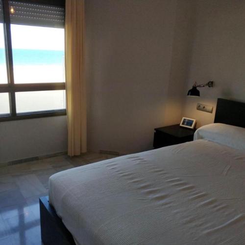 1 dormitorio con cama blanca y ventana en Victoria Beach Sunset Lounge, en Cádiz