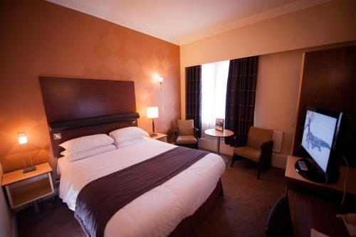 a hotel room with a bed and a flat screen tv at The Angel Hotel in Cardiff