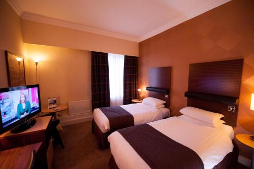 a hotel room with two beds and a flat screen tv at The Angel Hotel in Cardiff