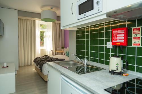 a kitchen with a sink and a room with a bed at Chic Studios in Parede