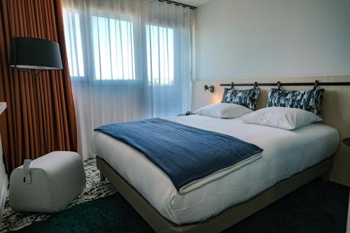 a bedroom with a large bed with a blue blanket at Live Hotels Bordeaux Lac in Bordeaux