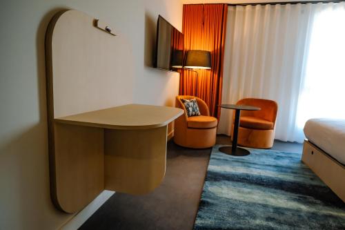 a hotel room with a bed and a desk and a chair at Live Hotels Bordeaux Lac in Bordeaux