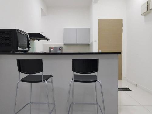 a kitchen with two bar stools and a microwave at Skypod Residence Puchong in Puchong