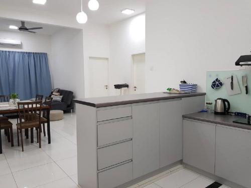 a kitchen with white cabinets and a living room at Skypod Residence Puchong in Puchong