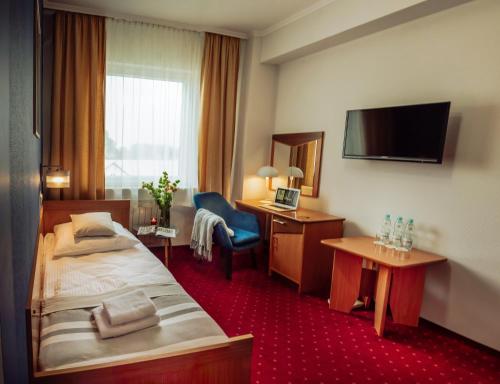 Habitación de hotel con cama, escritorio y TV. en Hotel Albatros, en Przemyśl