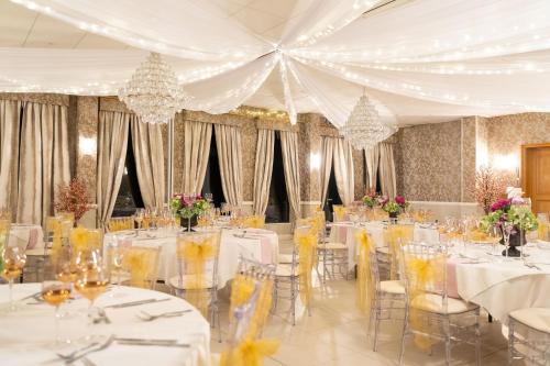 a banquet hall with white tables and chairs and flowers at Guildford Manor Hotel & Spa in Guildford