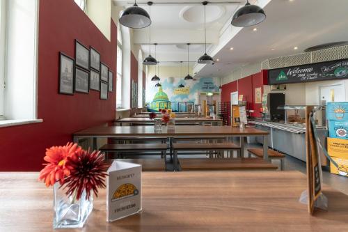 a fast food restaurant with wooden tables and a vase of flowers at YHA London St Paul's in London