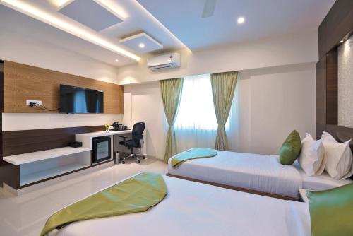 a hotel room with two beds and a tv at Vanusa Residency in Bengaluru