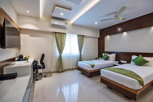 a hotel room with two beds and a television at Vanusa Residency in Bengaluru