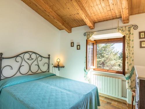 Un dormitorio con una cama azul y una ventana en Casa vacanze Il Poggetto, en Monticiano