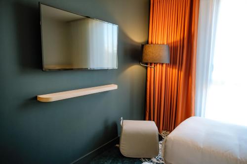 a bedroom with a bed and a television on the wall at Live Hotels Bordeaux Lac in Bordeaux