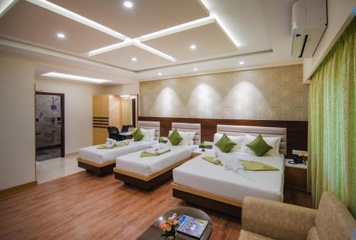 a hotel room with two beds and a couch at Vanusa Residency in Bengaluru