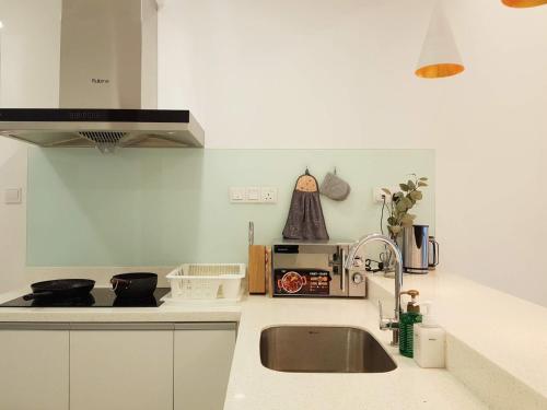 a white kitchen with a sink and a microwave at Skypod Residence Puchong in Puchong