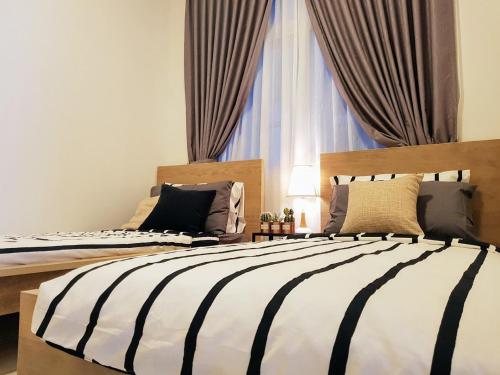 two beds in front of a window in a bedroom at Skypod Residence Puchong in Puchong