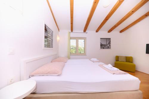 a white bedroom with a large bed and a yellow chair at Villa francesca in Starigrad
