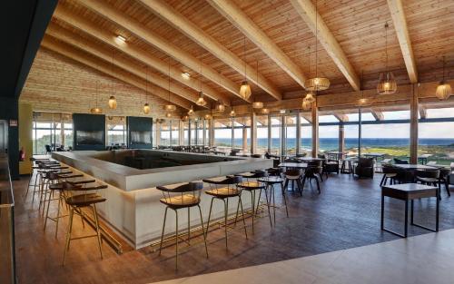ein Restaurant mit einer Bar mit Stühlen und Tischen in der Unterkunft West Cliffs Ocean and Golf Resort in Casal da Lagoa Seca