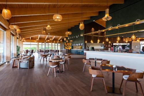 ein Restaurant mit Tischen und Stühlen und eine Bar in der Unterkunft West Cliffs Ocean and Golf Resort in Casal da Lagoa Seca