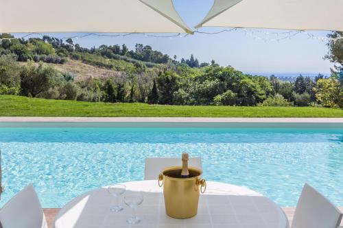 a table with wine glasses and an umbrella next to a pool at Villa Anna Maria in Centobuchi