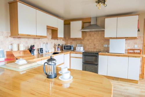 a kitchen with white cabinets and a wooden table at Henblas Holiday Cottages in Abergele
