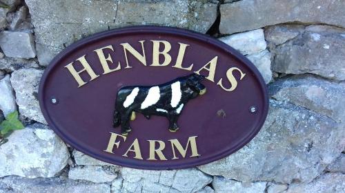 a sign for a farm on a stone wall at Henblas Holiday Cottages in Abergele