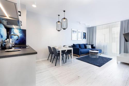 コウォブジェクにあるApartamenty BLIŻEJ MORZA Siłownia i Taras Widokowy Kołobrzeg by Noclegi Rentersのキッチン、リビングルーム(青いソファ、テーブル付)