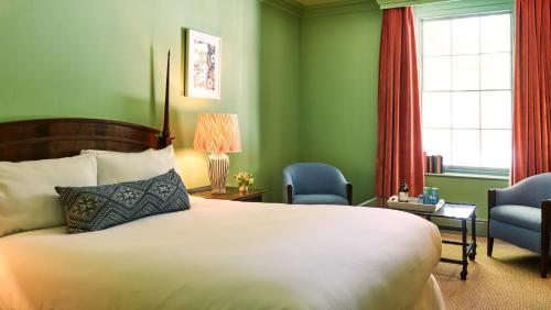 a hotel room with a bed and two chairs at The Mitre, Hampton Court in Kingston upon Thames